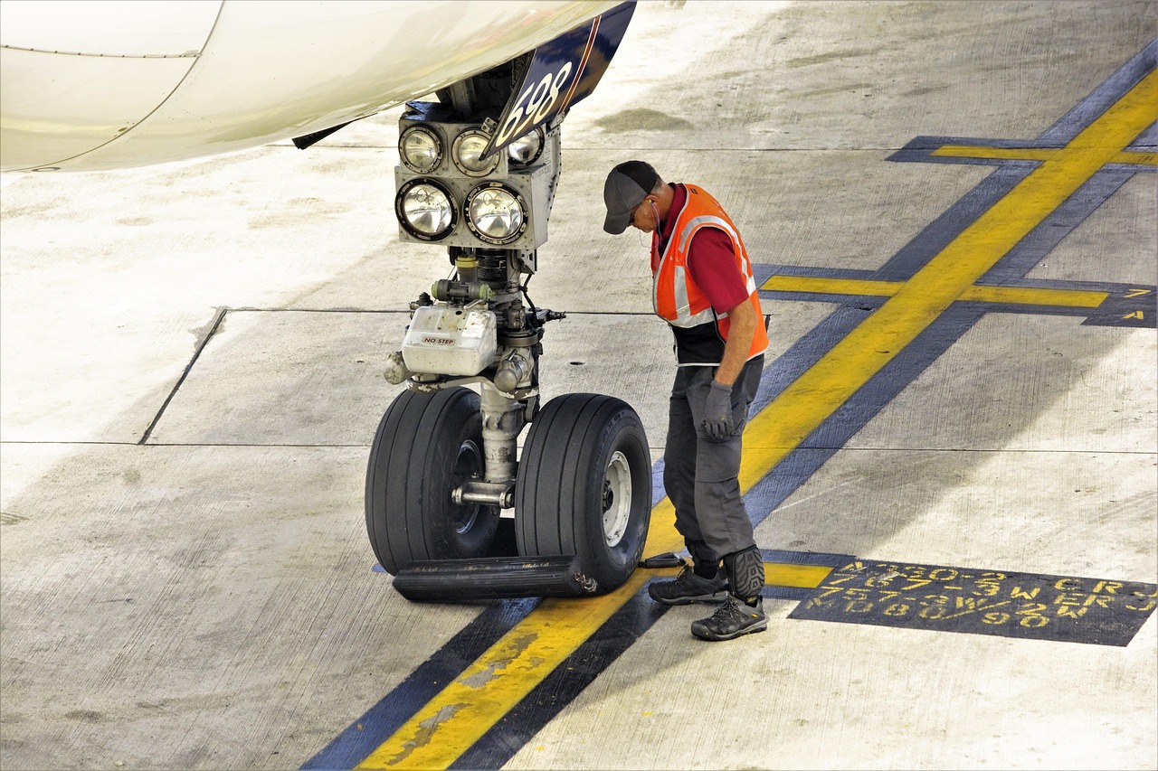 landing gear, nose wheels, commercial, airliner, gate, worker, setting, wheel blocks, chocks, aircraft, maintenance, aircraft mechanic, nose gear, large tires, tires, airport, aviation, travel, terminal, airplane, aircraft mechanic, aircraft mechanic, aircraft mechanic, aircraft mechanic, aircraft mechanic